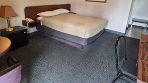 A hotel room with a bed, a desk, a chair, a lamp, a phone, and a painting on the wall. - Algonquin Motor Lodge (Edmonton)