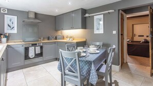 Une cuisine moderne avec des meubles gris, une table à manger dressée avec des assiettes et des couverts, et un four visible.