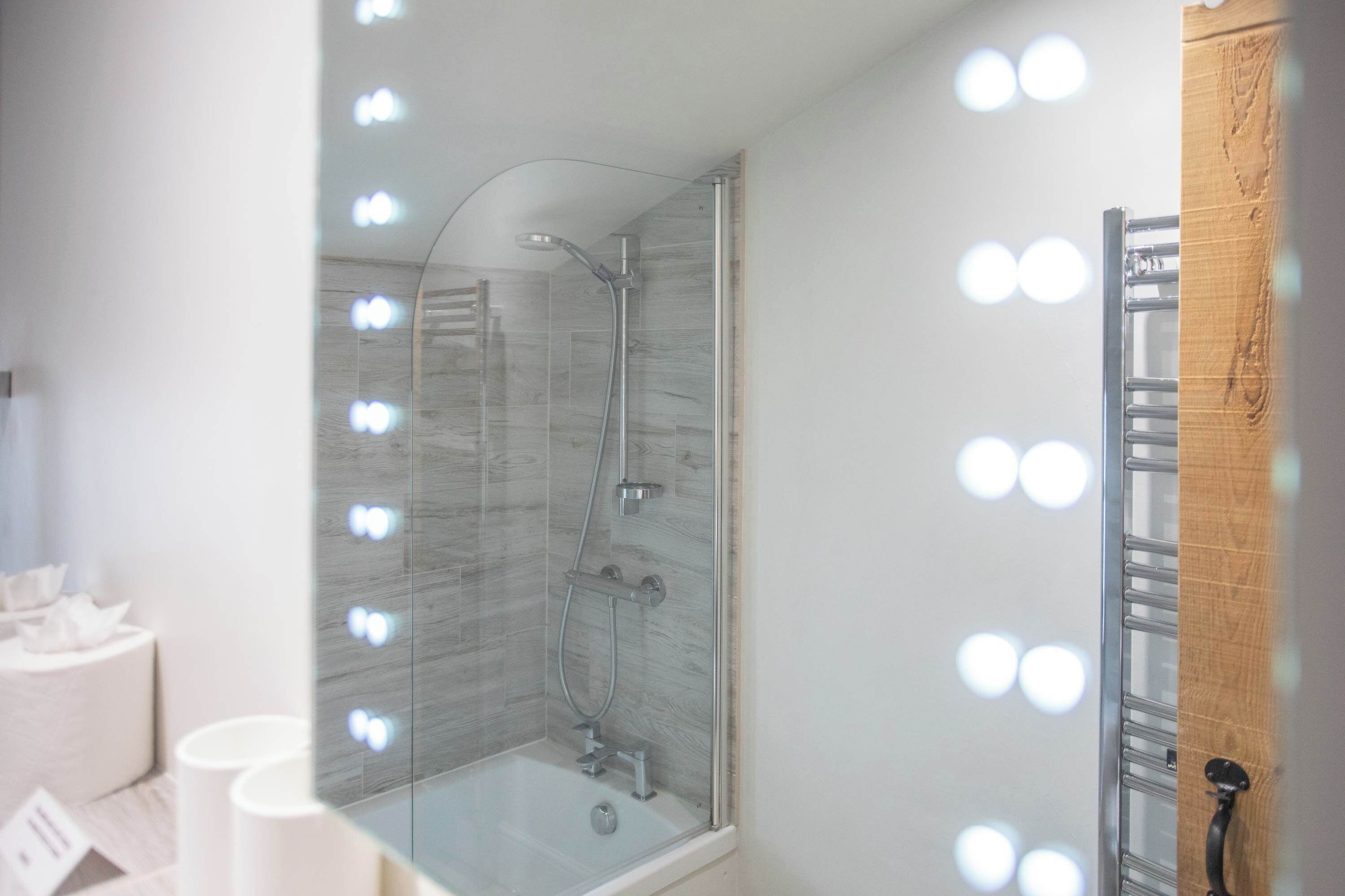 A bathroom with a glass-enclosed shower, a vanity with a mirror, and a towel rack.