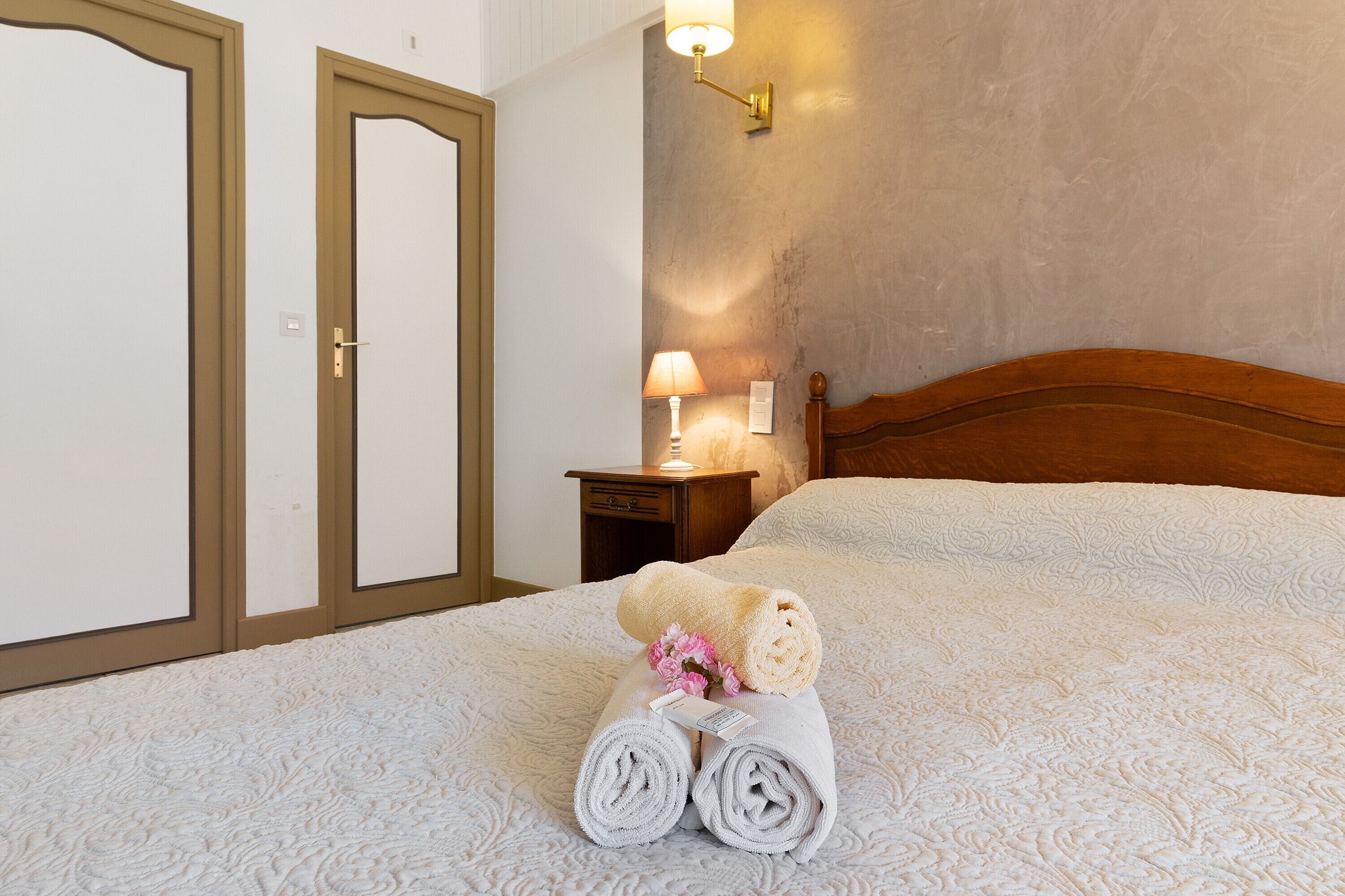 Une chambre d’hôtel avec un lit, une table de chevet avec une lampe et un luminaire fixé au mur.