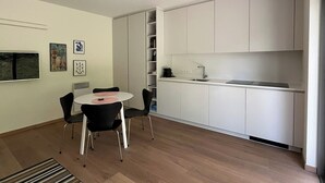 Eine moderne Küche mit weißen Schränken, einem runden Esstisch mit Stühlen und einer kleinen Kücheninsel.