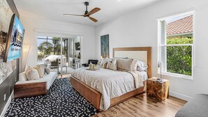 A bedroom with a bed, a desk, a chair, a window, and a ceiling fan. - Heated Pool, Gulf Access & Waterfront Luxury Escape - Seaside Social - Roelens (Cape Coral)