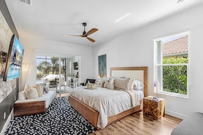 Ein Schlafzimmer mit Bett, Schreibtisch, Stuhl, Fenster und Deckenventilator.