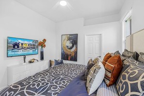 A bedroom with a bed, a TV, a painting, and a window. - Heated Pool, Gulf Access & Waterfront Luxury Escape - Seaside Social - Roelens (Cape Coral)