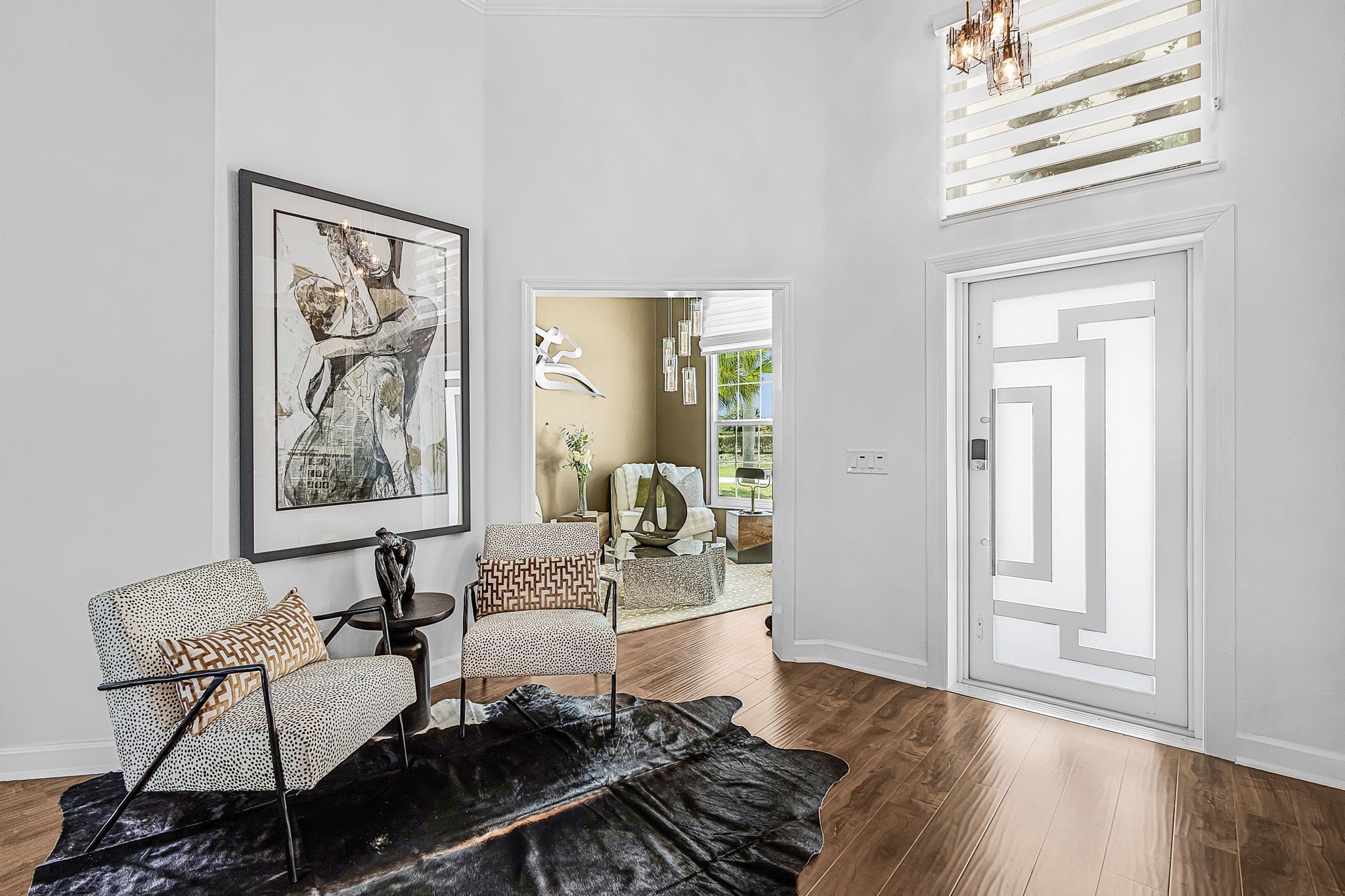 A modern living room with a large abstract painting, two patterned armchairs, a coffee table, and a black leather rug.