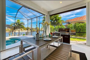 Eine Terrasse mit Pool, Grill und Esstisch.