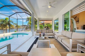 Ein modernes Wohnzimmer mit Pool, großen Fenstern und Deckenventilator.