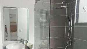 A modern bathroom with a glass-enclosed shower, a white sink, and a wooden vanity. - 1 bedroom and 1 bathroom apartment in Monte Vista, Sosúa (Sosúa)
