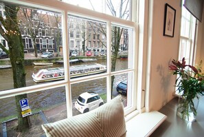 Een uitzicht op een gracht, een witte auto en een gebouw met een blauw bord.