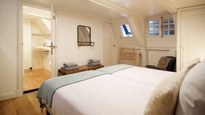 A bedroom with a bed, a bedside table with towels, a mirror, a window, and a door leading to a bathroom. - Sonnenberg - Canal side & view - Private & Central (Amsterdam)