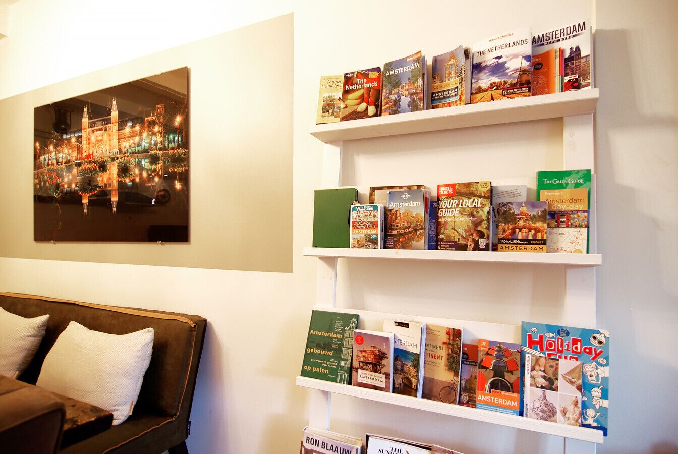 Een kamer met een bank, een aan de muur hangend schilderij en planken vol reisboeken.