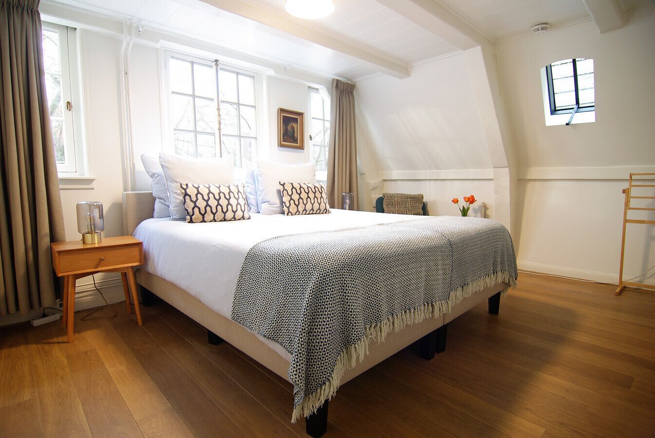 A bedroom with a bed, bedside table, and a window.