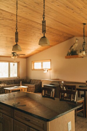 Een keuken met houten kasten, een centraal eiland en hanglampen.
