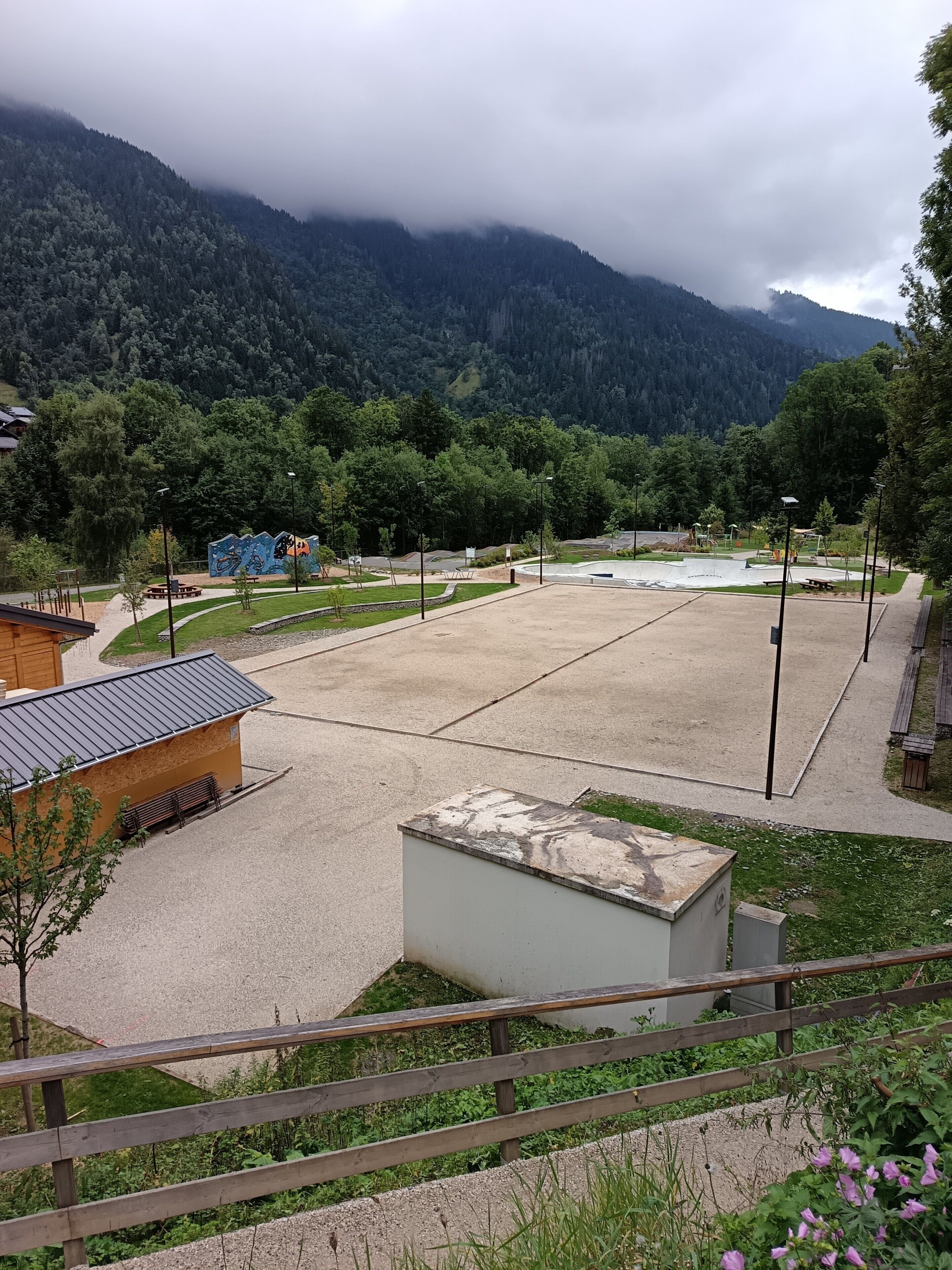 Un parc avec une aire de jeux, un petit bâtiment et une vue sur les montagnes.