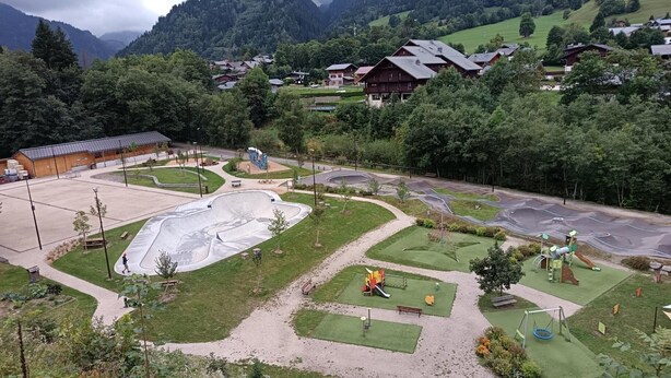 Un parque con una zona de skate, área de juegos y senderos peatonales.