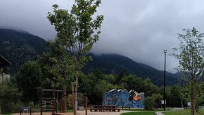 Un parque infantil con un área de escalada, mesas de picnic y un mural de fondo.