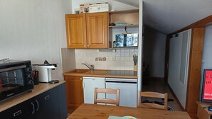 Una cocina compacta con microondas, tostadora, lavabo y armarios de madera.