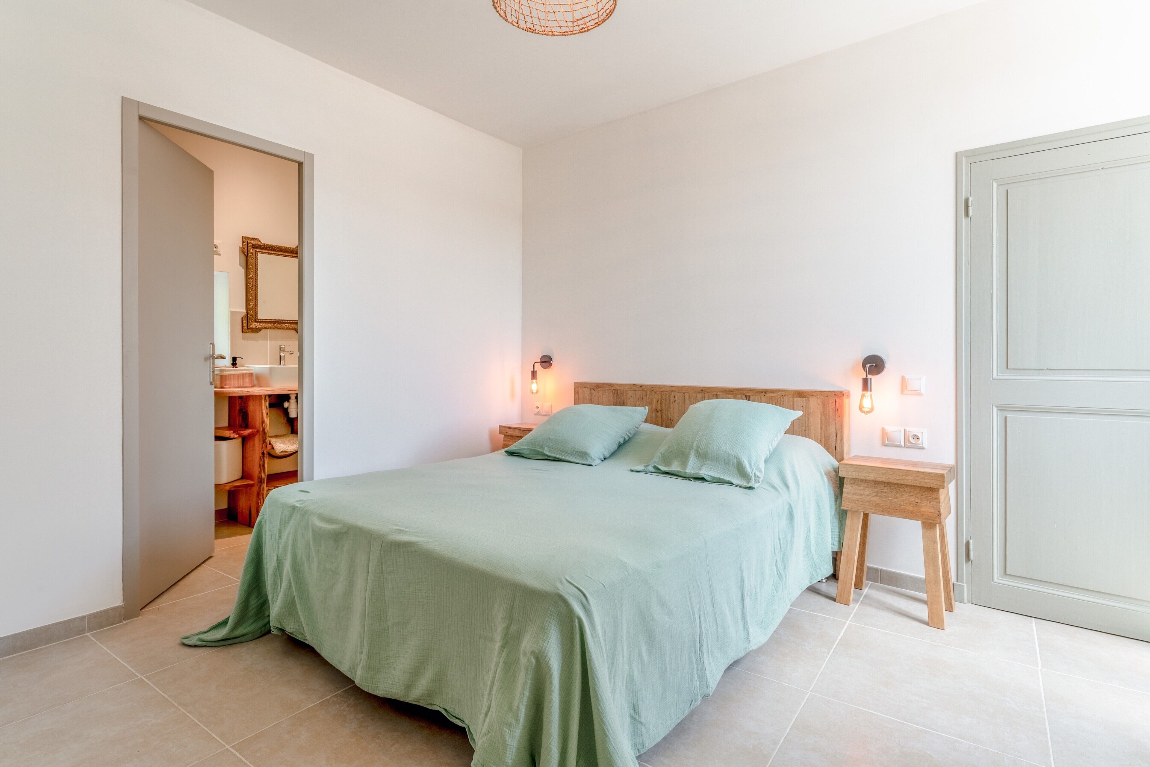 Une chambre à coucher avec un lit, des tables de chevet, une commode, une tête de lit en bois et une porte.