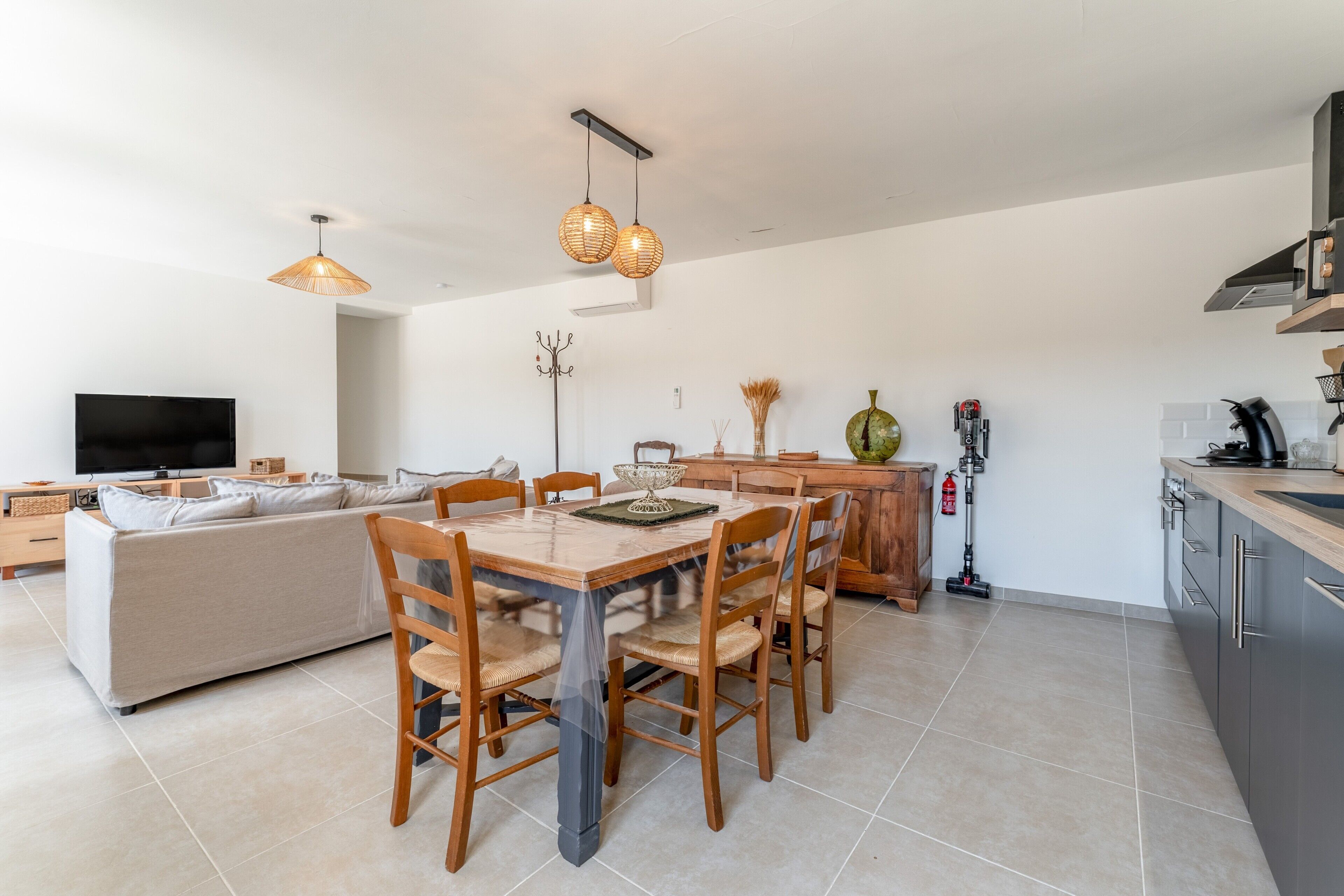 Una sala de estar moderna con sofá, mesa de comedor, sillas y televisor.