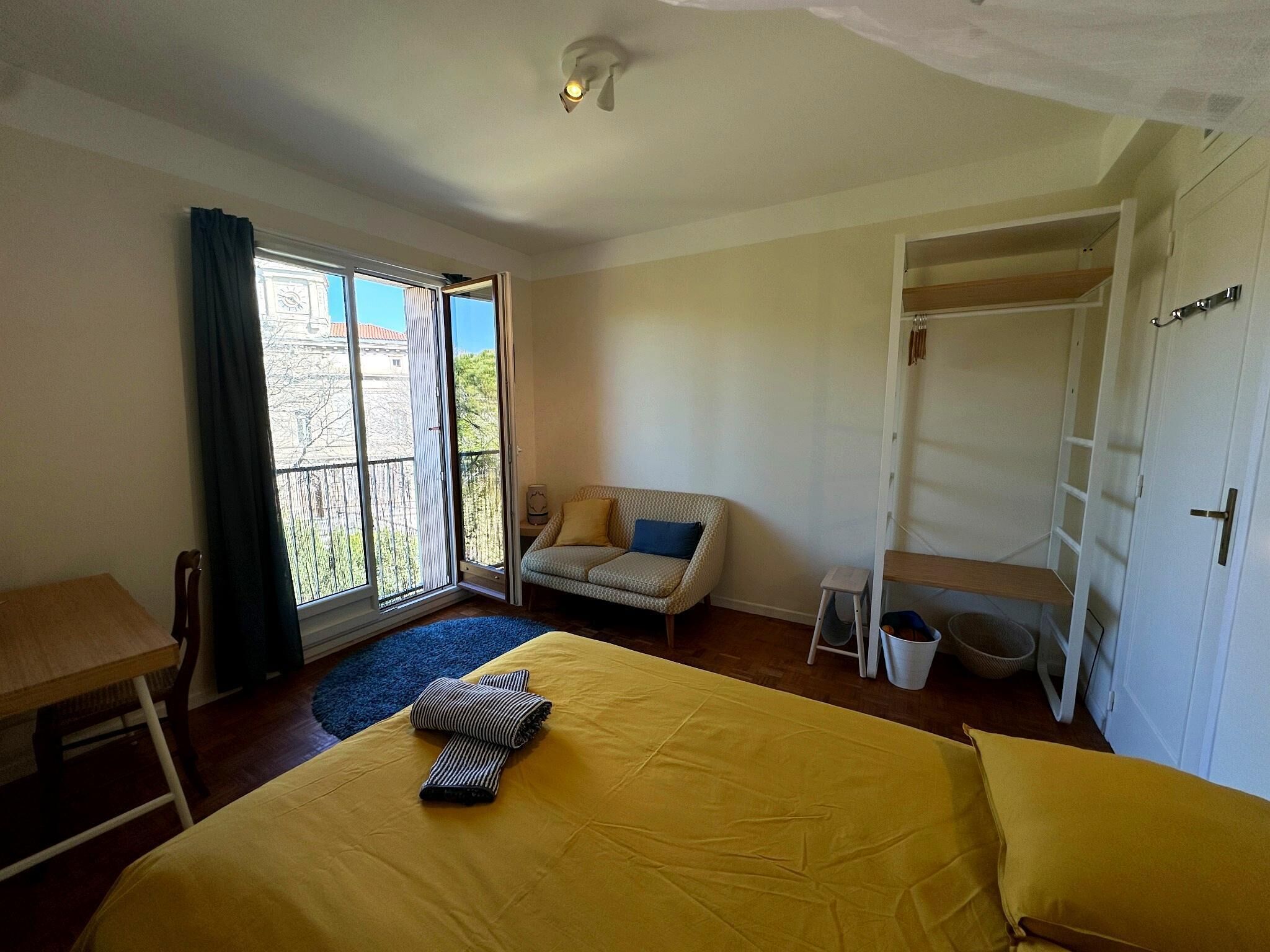 Une chambre à coucher comprenant un lit, un canapé, une petite table, une chaise, une armoire et un balcon.