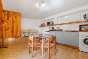 A compact kitchen with a dining area, wooden cabinets, a microwave, and a washing machine. - Holiday Apartment "La Chambrette" in the Heart of Blieux (Blieux)