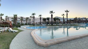 Una piscina con sillas de descanso y palmeras.