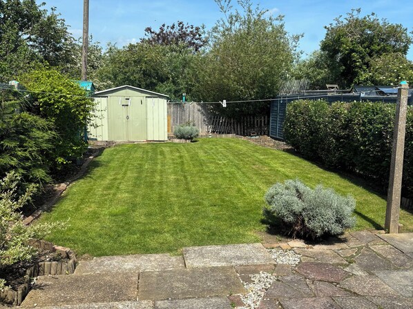 A well-maintained lawn, a shed, and a fenced area with dense shrubbery. - Herby's Retreat (Mablethorpe)
