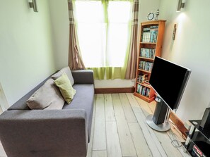 Ein Wohnzimmer mit einer Couch, einem Bücherregal und einem Fernseher.