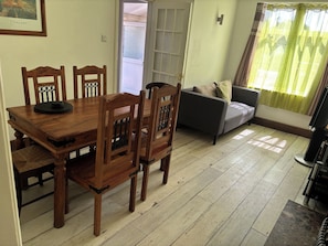 A dining area with a wooden table and chairs, a sofa, and a television. - Herby's Retreat (Mablethorpe)