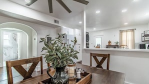 A modern kitchen with white cabinets, a wooden dining table, and a ceiling fan. - Tranquil Terrace - Whole Duplex (Corpus Christi)