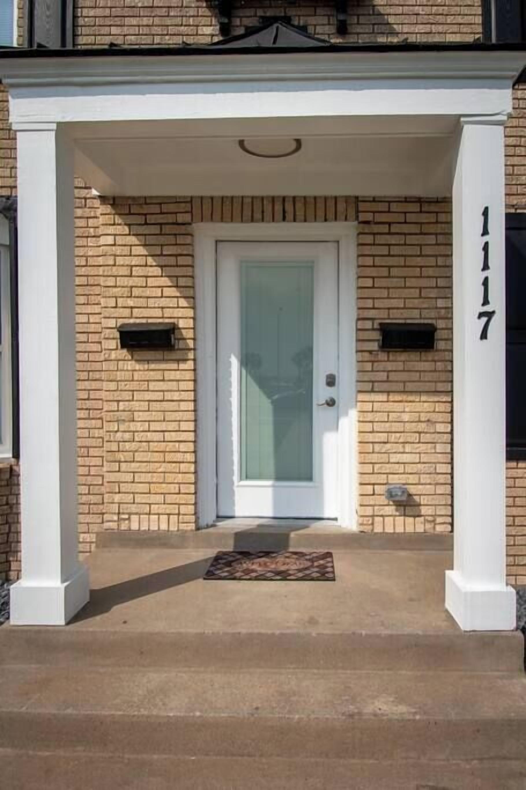 A brick building with a white door and a number "1117" on the right.