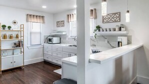 A modern kitchen with white cabinetry, a built-in microwave, and pendant lighting. - Tranquil Terrace - Whole Duplex (Corpus Christi)