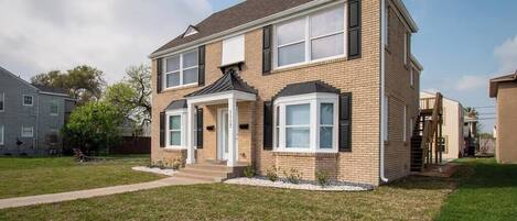 A two-story house with a brick facade, a front porch, and a well-maintained lawn.