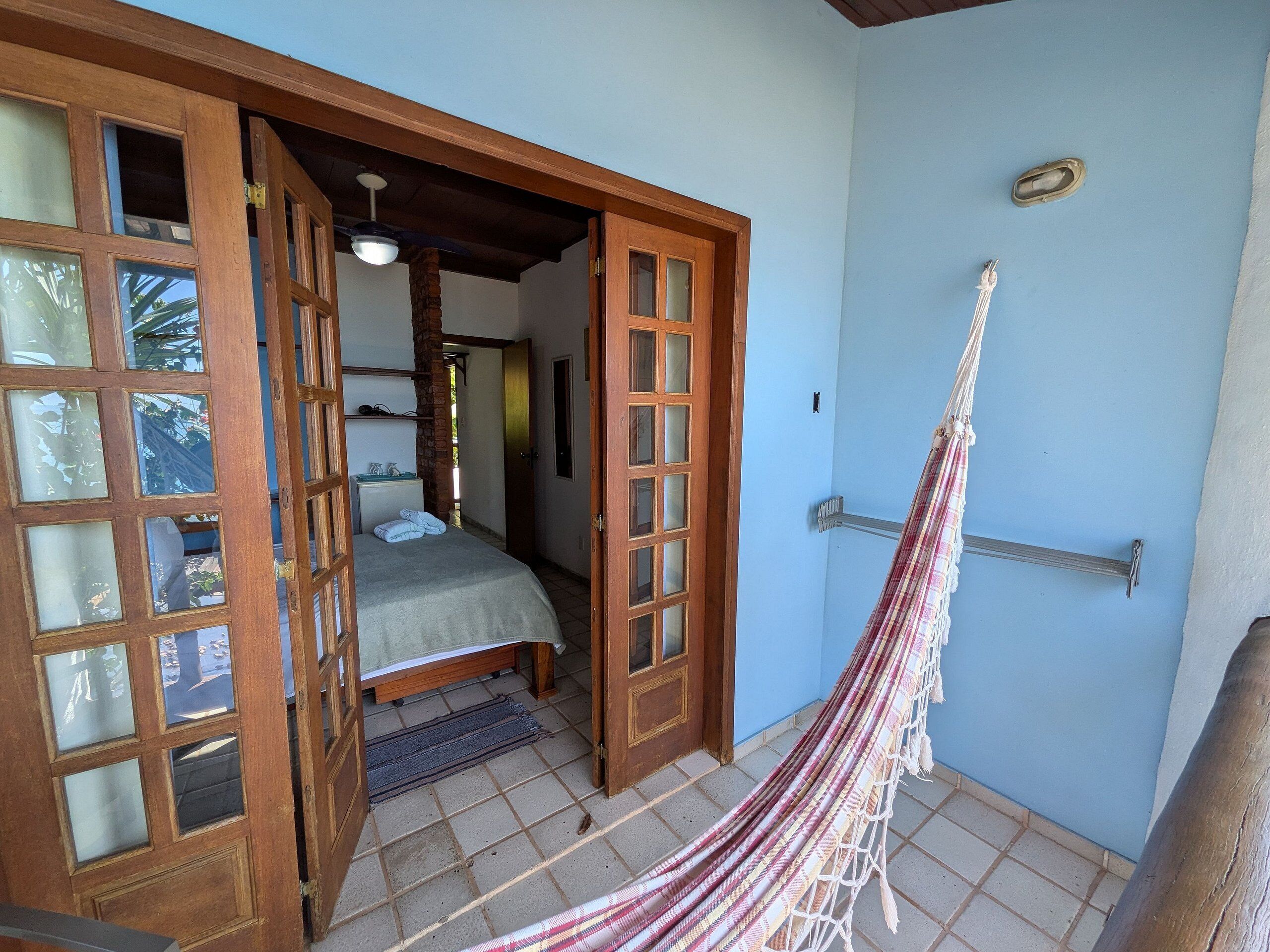Una habitación con una cama, una hamaca y una puerta que da a otra habitación.