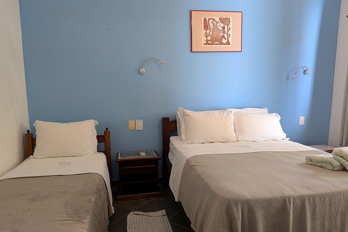 Una habitación con dos camas, una mesita, un tapete y un cuadro enmarcado en la pared.