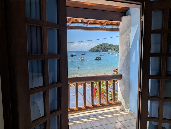 Un balcón con vista a barcos en el agua y una montaña al fondo.