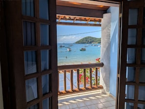 Un balcón con vista a barcos en el agua y una montaña al fondo.