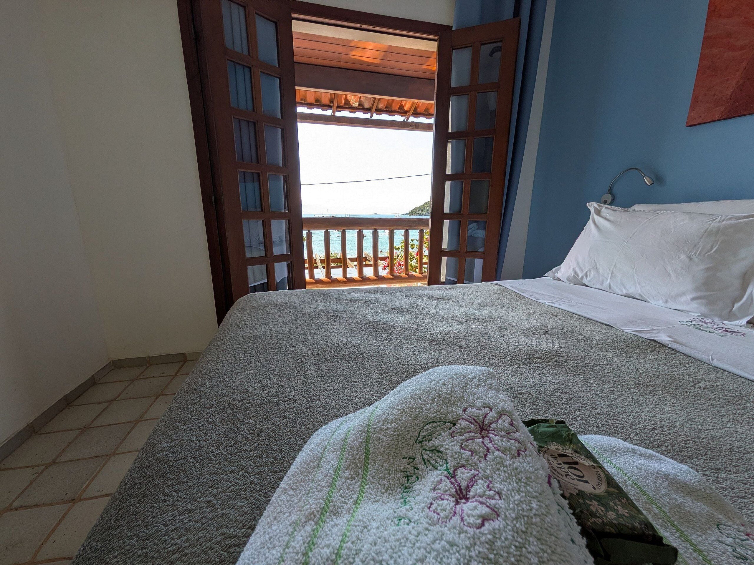 Une chambre à coucher avec un lit, une fenêtre donnant sur un beau paysage et une porte menant à l’extérieur.