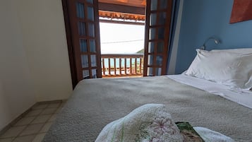 A bedroom with a bed, a window with a view, and a door leading outside.