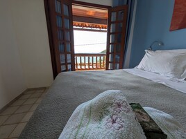 Un dormitorio con cama, ventana con vistas y puerta que da al exterior.