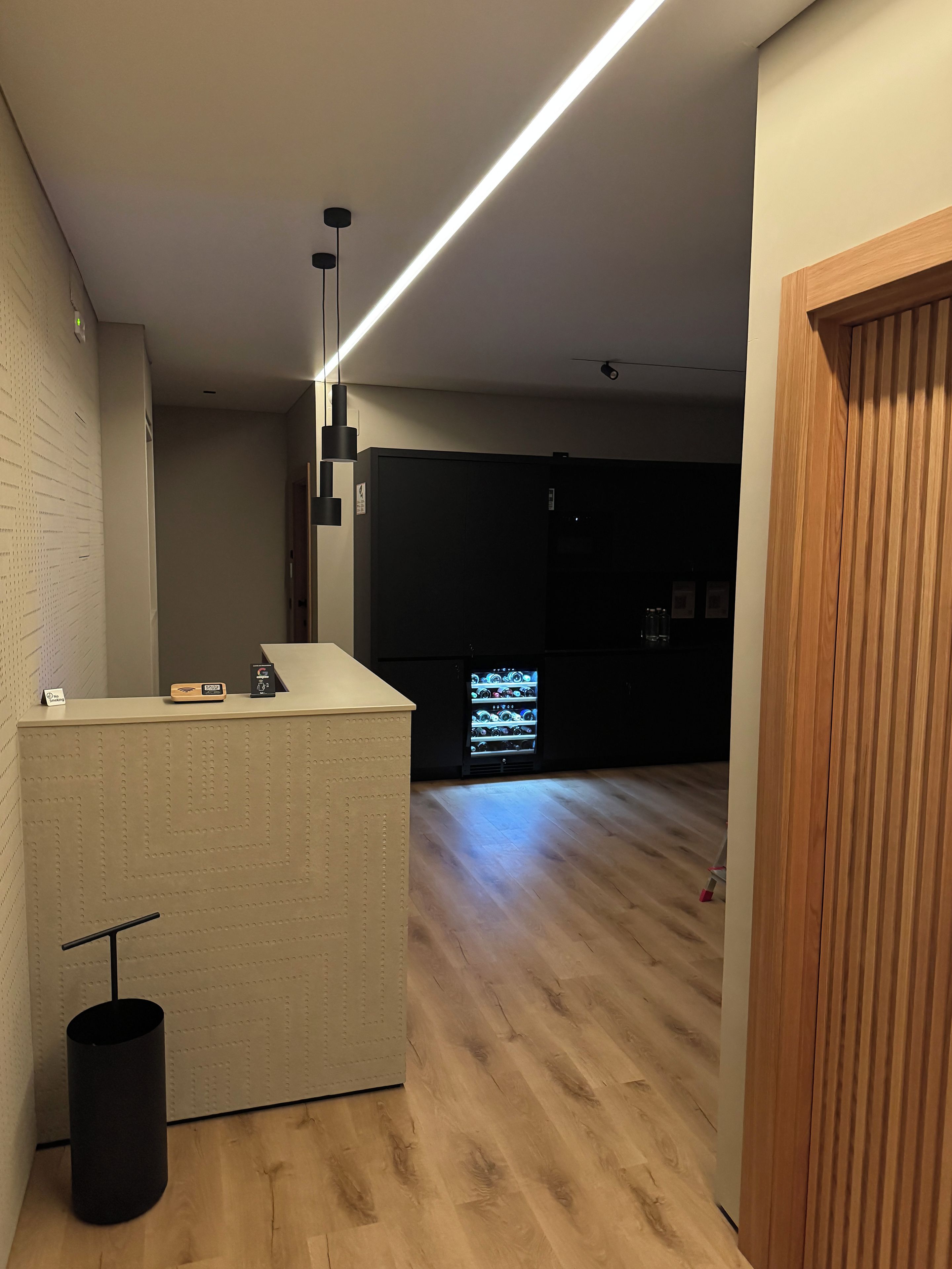 A modern kitchen with a wooden countertop, a black trash bin, and a refrigerator in the background.