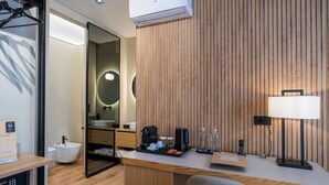 A modern bathroom with a freestanding bathtub, a mirror with a round light, a toilet, and a shower area.