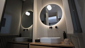 A modern bathroom with two sinks, a large mirror, and a towel dispenser.