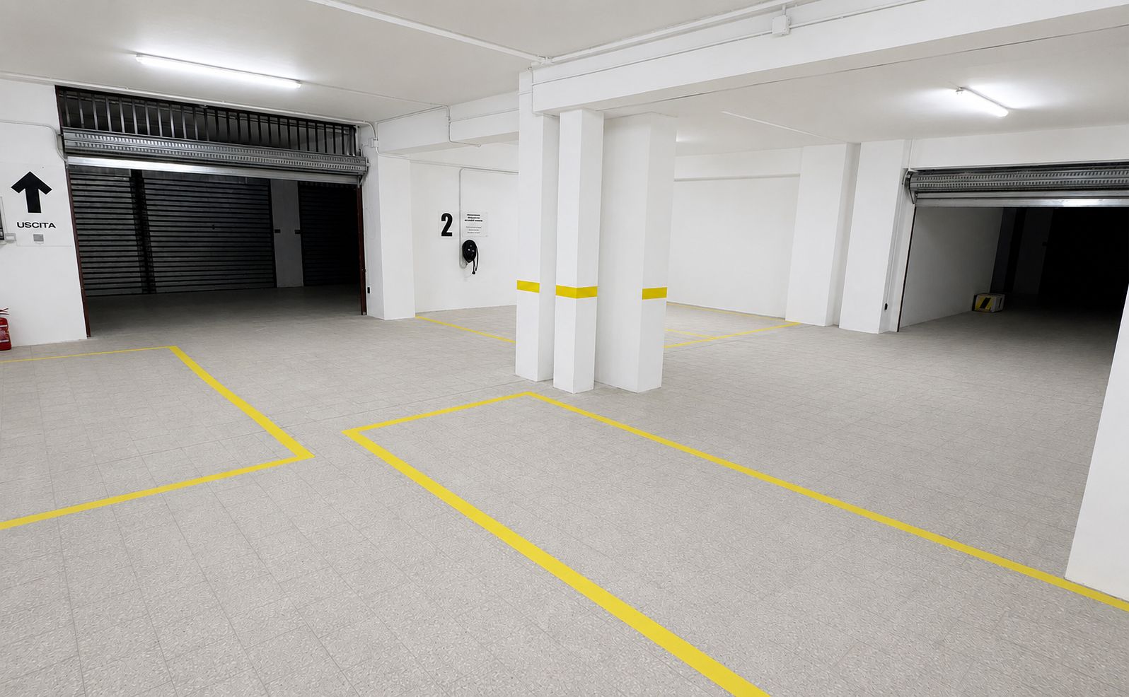 A clean, empty parking garage with marked parking spaces and a fire extinguisher.