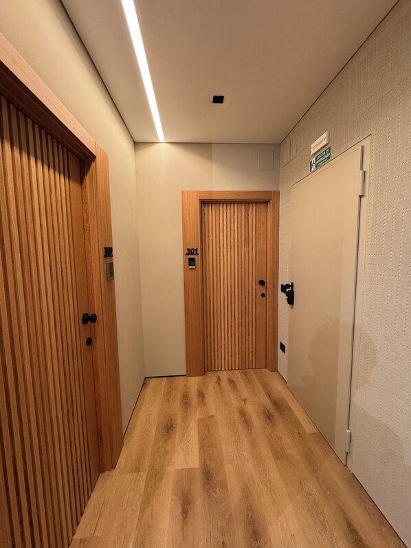 Un pasillo con puertas de madera, un cartel que indica el número 301 y una pared con textura.