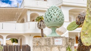 Un edificio con fachada blanca, balcones arqueados y una escultura de cactus.