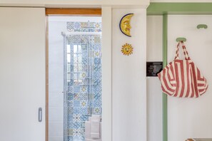 Ein Zimmer mit Duschbereich mit Fliesen, einer Tür mit Griff und einer Wand mit Mond und Sonnendekoration.