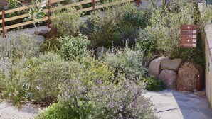 A garden area with a wooden fence, a stone pathway, and a sign indicating directions to the apartment and garage. - In a Residence, Air-conditioned, With Terrace (Marone)