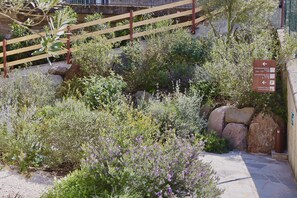 A garden area with a wooden fence, a stone pathway, and a sign indicating directions to the apartment and garage. - In a Residence, Air-conditioned, With Terrace (Marone)