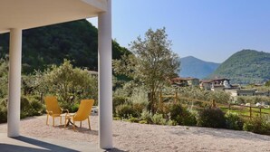A covered outdoor seating area with two chairs, a gravel ground, and a view of houses and hills in the background. - In a Residence, Air-conditioned, With Terrace (Marone)